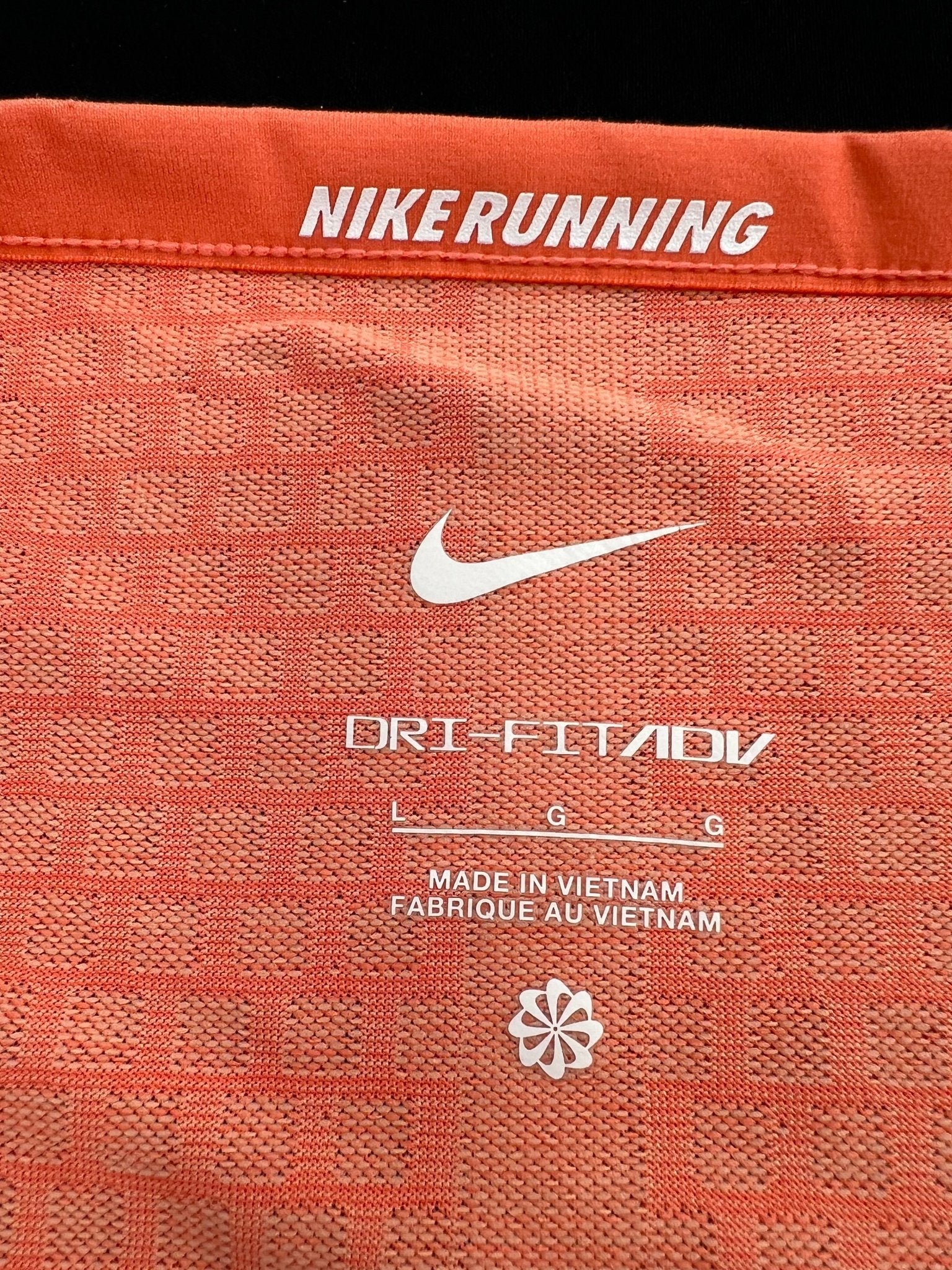 Close-up of Nike Running logo and Dri-FIT ADV label inside orange t-shirt