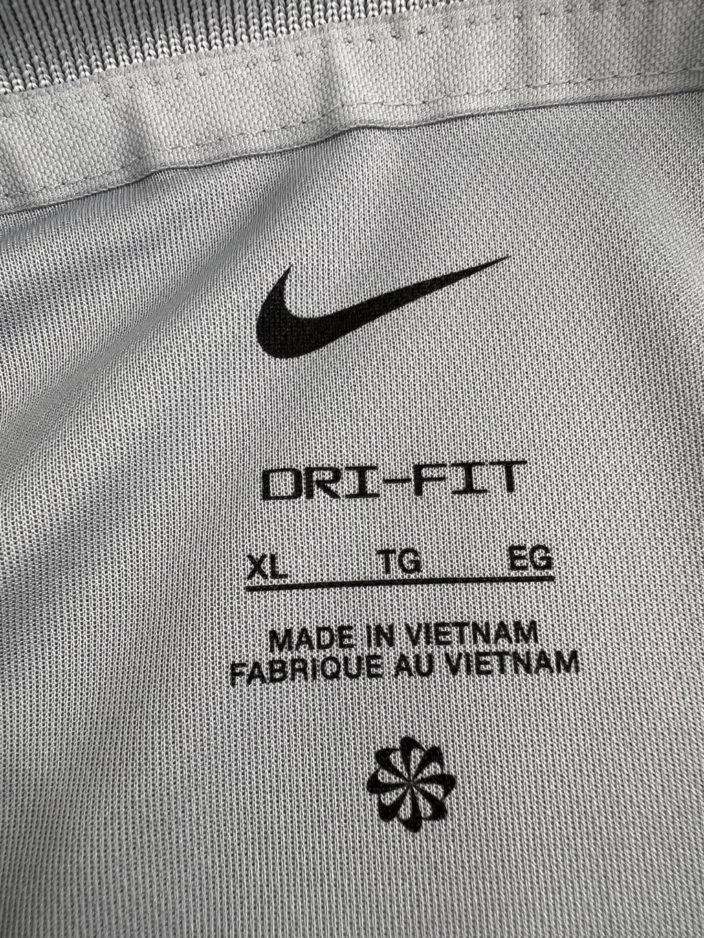 Close-up of inner Dri-FIT label in Nike men's light grey polo showing size XL and made in Vietnam
