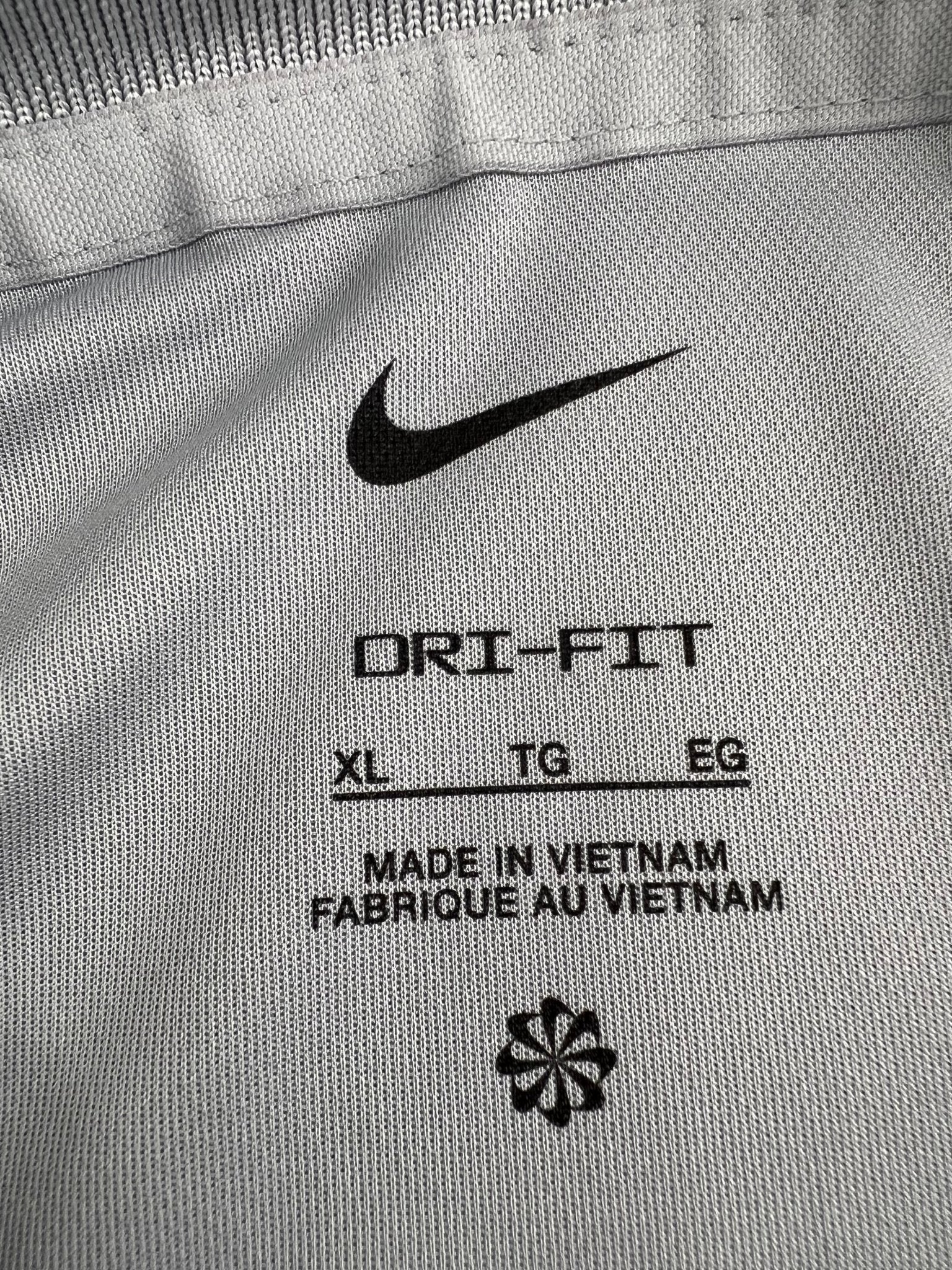 Close-up of inner Dri-FIT label in Nike men's light grey polo showing size XL and made in Vietnam
