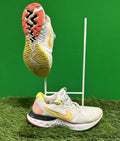 Nike Renew trainers in white with yellow accents and dual-tone outsole, shown on grass background