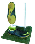 Black and yellow indoor football boots with non-marking sole, displayed on artificial grass
