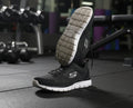 Pair of black Skechers mesh trainers with white soles, one shoe upright and one showcasing the textured sole