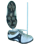 Pair of white and black FootJoy golf shoes with spiked soles displayed on artificial grass