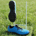 Pair of blue trail running shoes with grippy black soles displayed on artificial grass