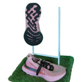 Pair of Nike pink and black trainers with unique sole, displayed on stand with green background