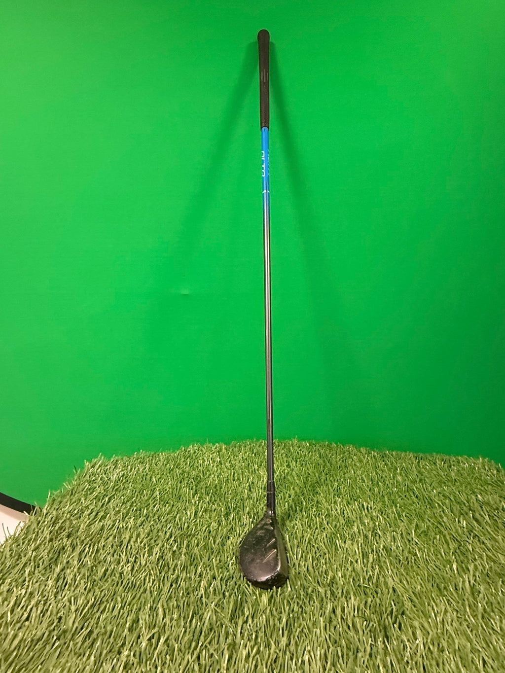 Ping 5 hybrid golf club standing upright on artificial grass with green background