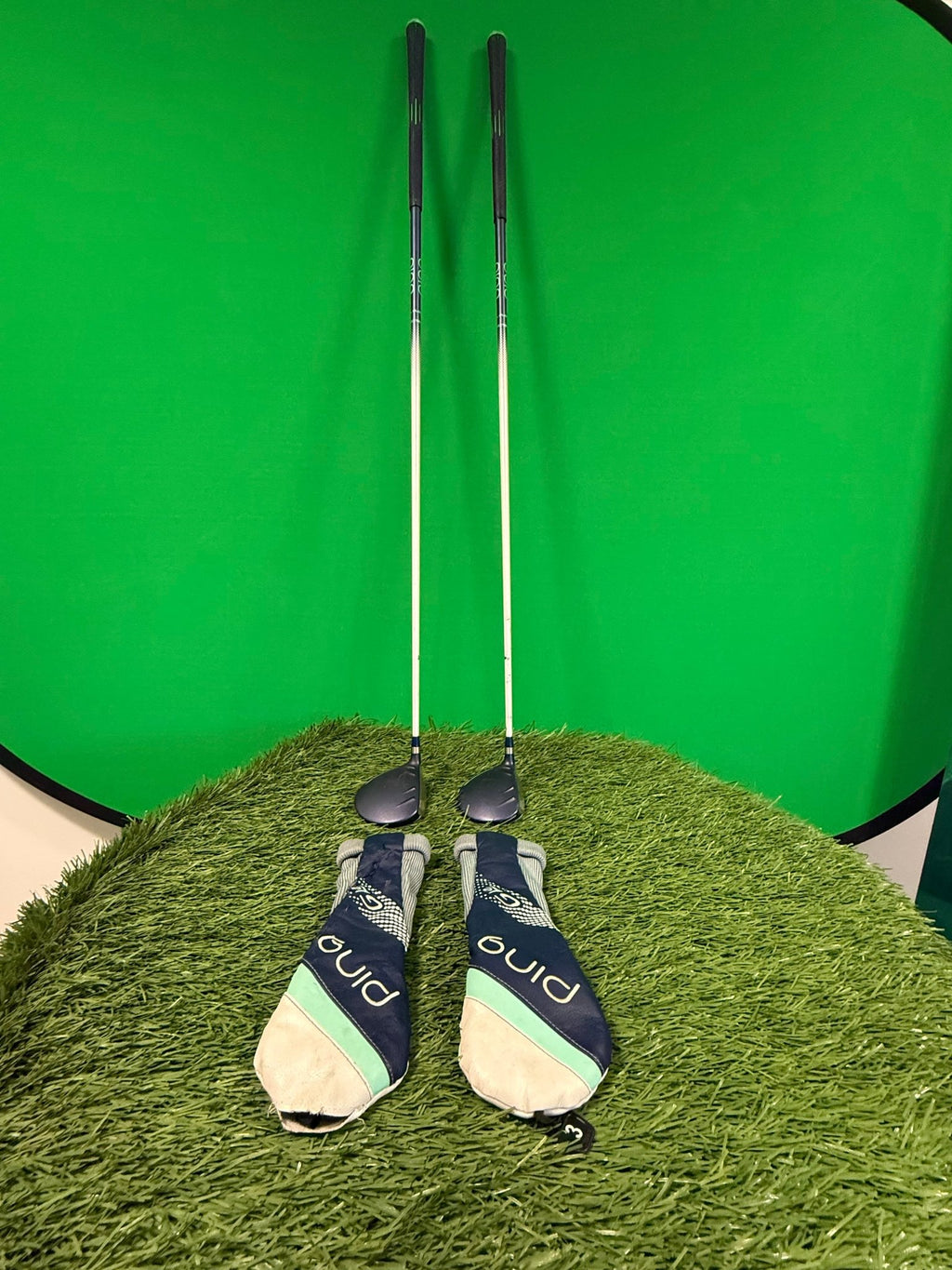 Ping Gle Women's 3 wood and 5 wood golf clubs with headcovers standing upright on artificial turf