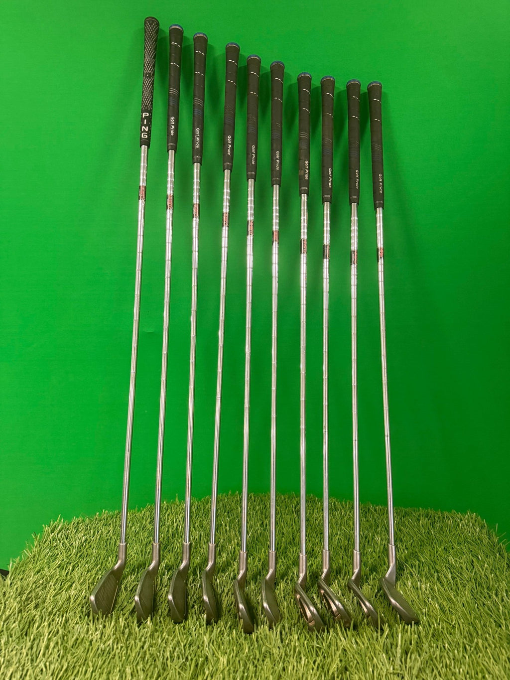 Full Ping i3 iron set 2-sw with clubs arranged on green turf, showcasing the grips and clubheads.