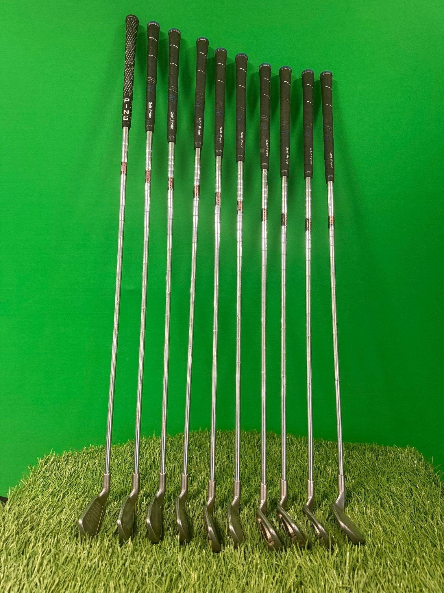 Full Ping i3 iron set 2-sw with clubs arranged on green turf, showcasing the grips and clubheads.