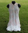 Front view of Puma sleeveless pink and white golf dress set with white shorts on grass