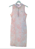 Front view of Puma golf dress in bright white and rose dust with zip neck, hanging outdoors.