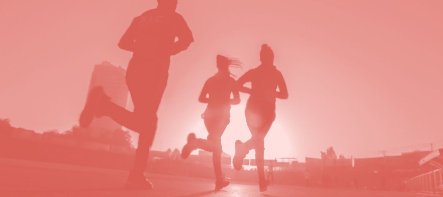 Red silhouette of runners on a track with a blurred background