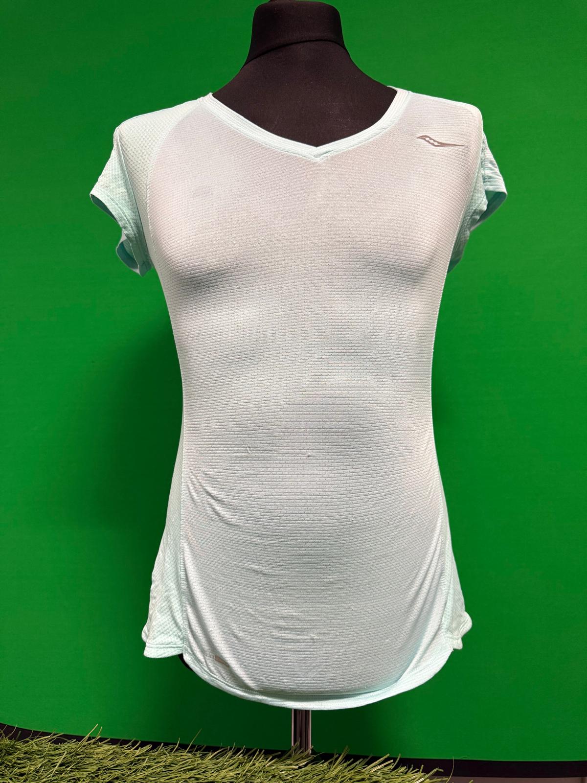 Front view of a Saucony women's light blue v-neck performance top displayed on a mannequin with a green background