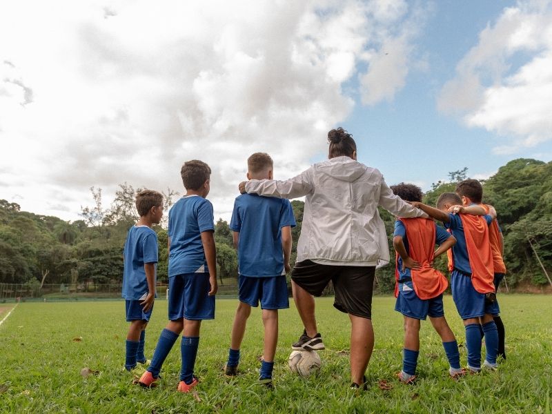Coach with young soccer players on a field under a cloudy sky