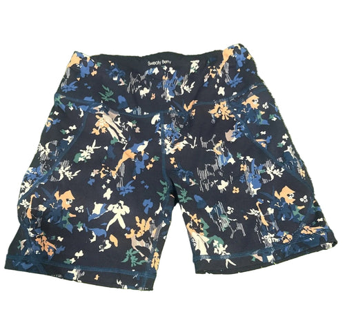 Sweaty Betty navy floral print active shorts laid flat on green surface