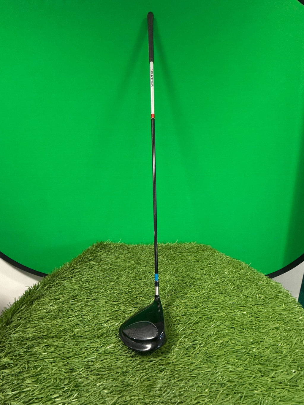 Used TaylorMade Burner driver golf club standing on artificial grass with a green background