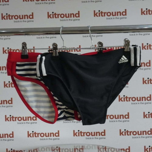 Two pairs of swimming trunks, adidas black with stripes and Seobean red with navy stripes displayed on hanger