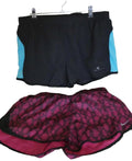Pair of Ronhill black shorts with blue side panels and Nike pink patterned shorts displayed on grass