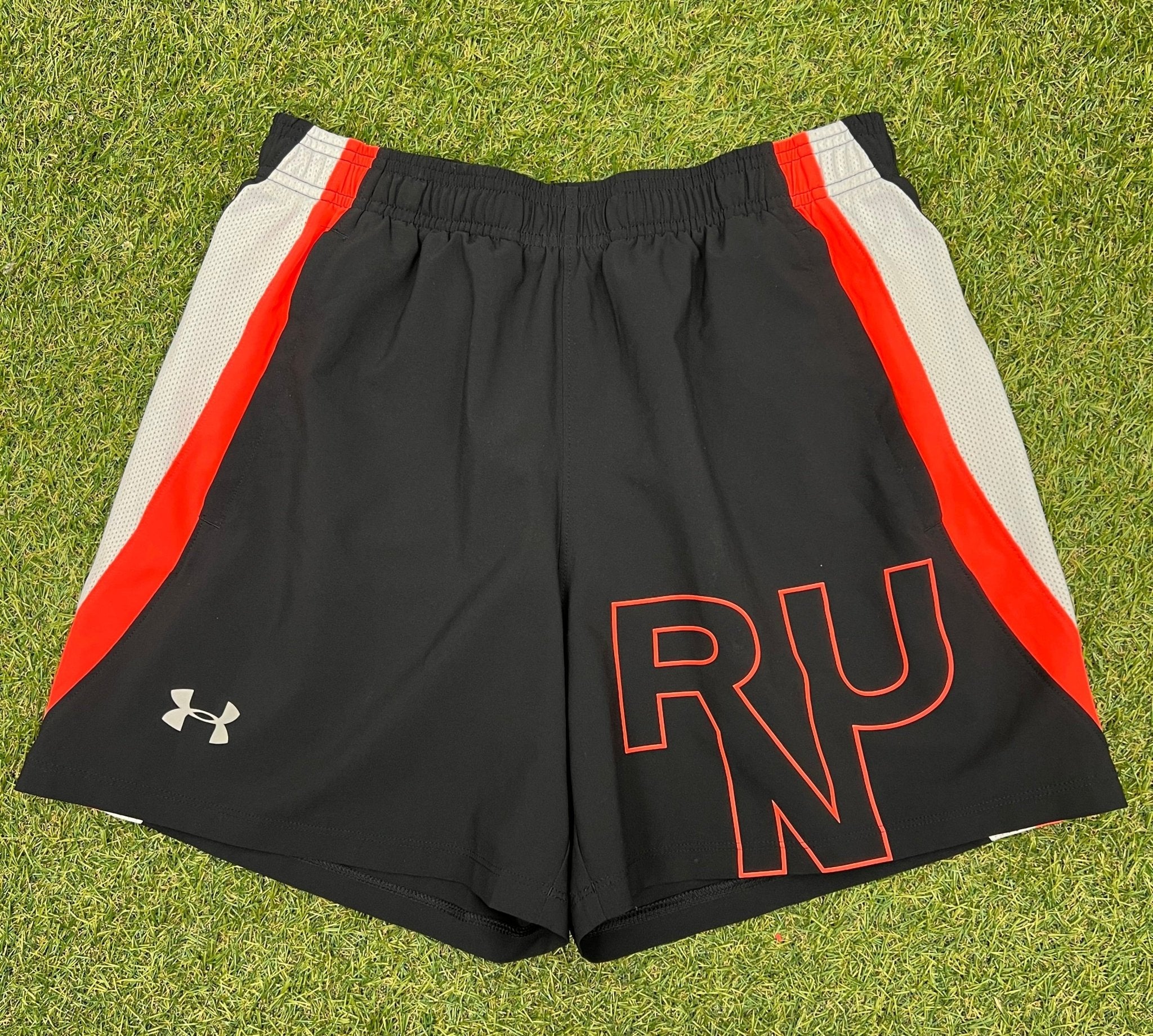 Front view of black Under Armour running shorts with red and white mesh side panels