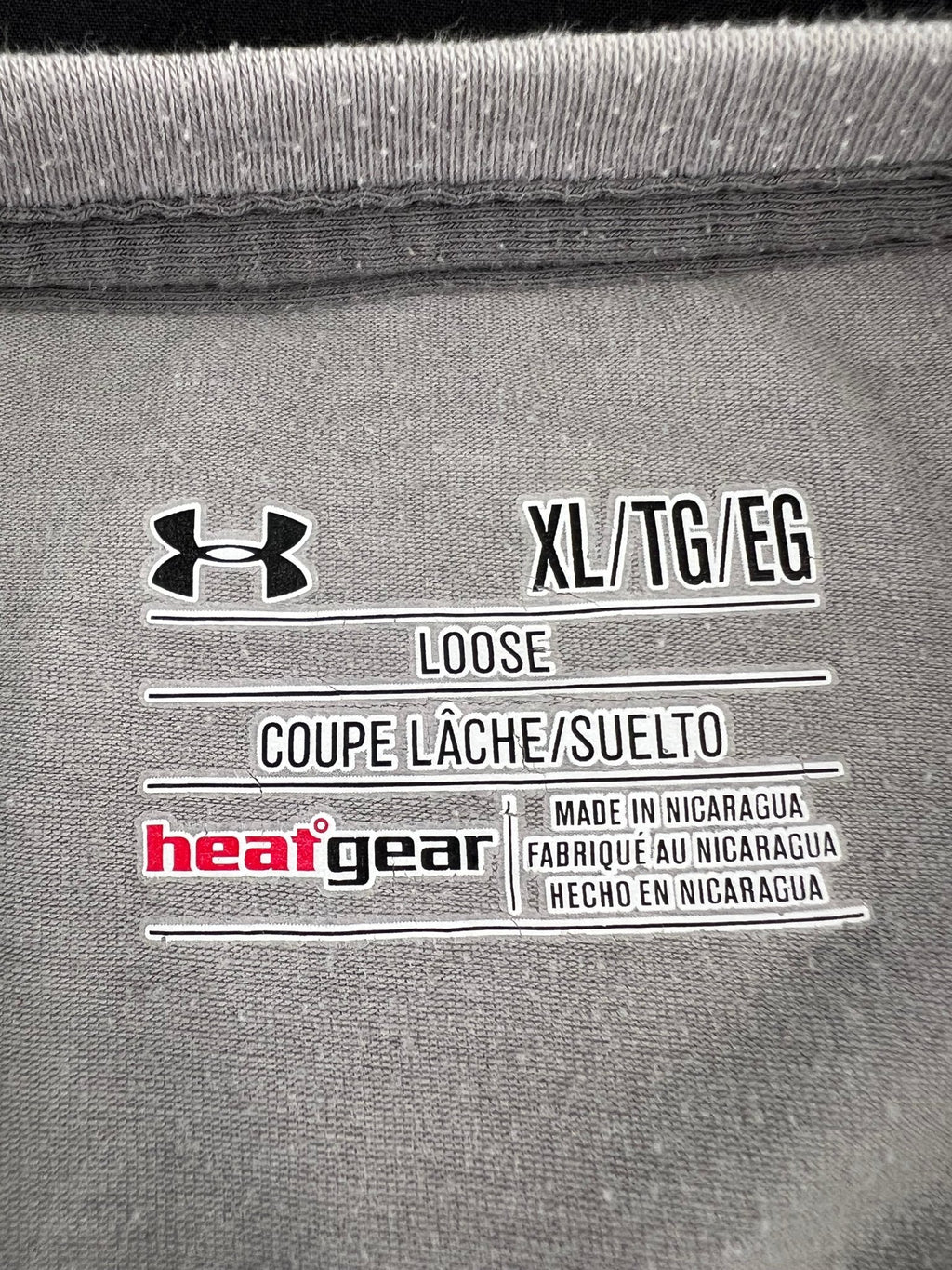 Close-up of Under Armour HeatGear loose fit XL size tag inside shirt