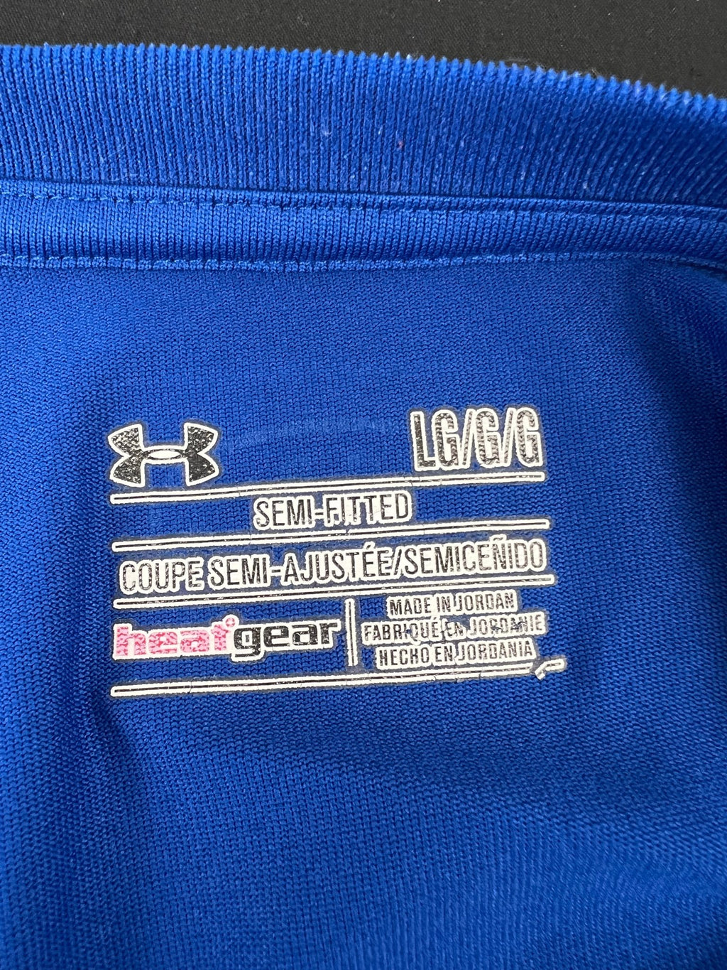 Close-up of the Under Armour label inside the blue semi-fitted V-neck T-shirt showing size and fabric details