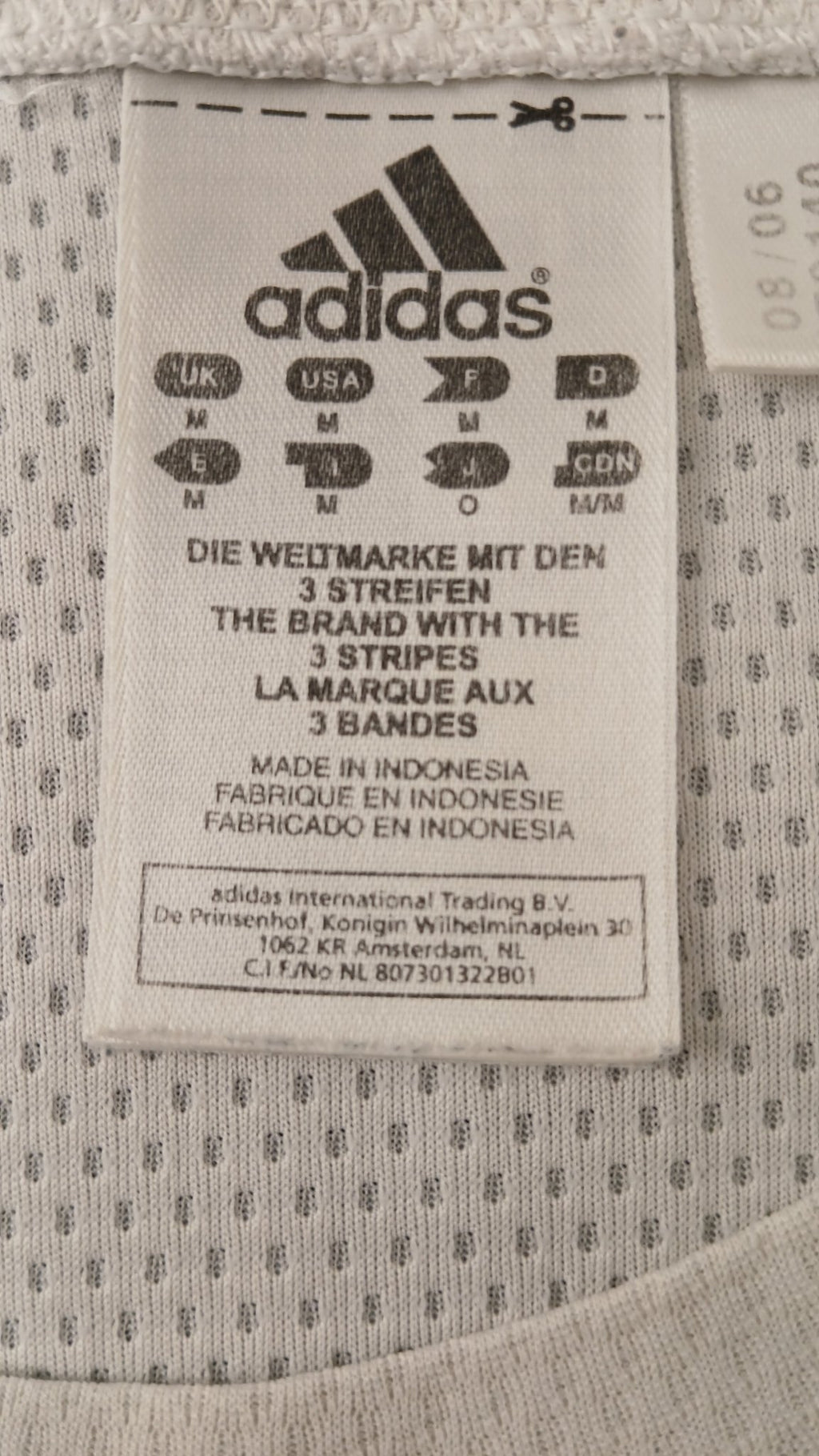 Close-up of adidas logo and size tag on white t-shirt