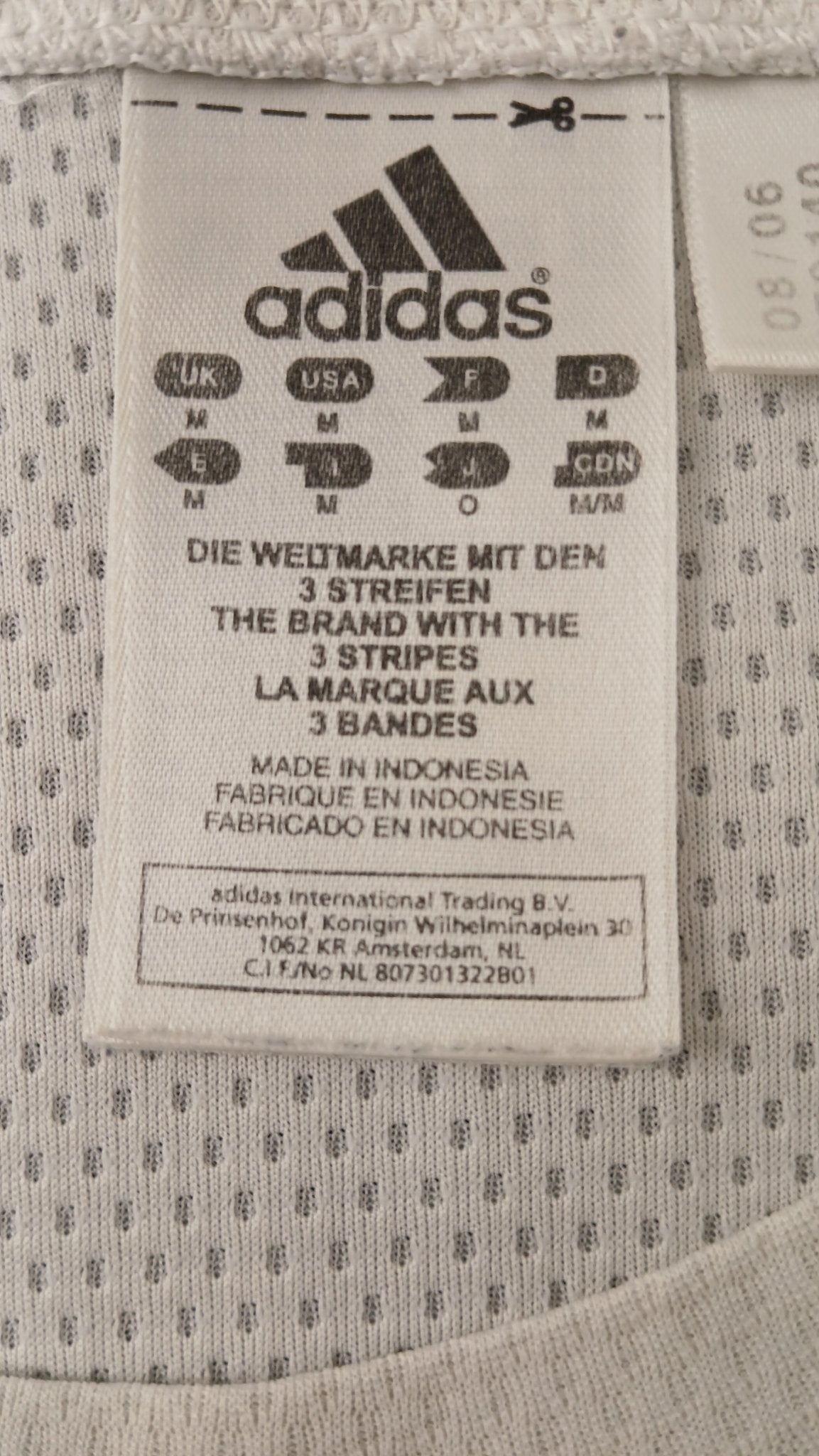 Close-up of adidas logo and size tag on white t-shirt