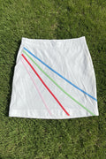 Front view of a white Green Lamb golf skirt with diagonal pastel stripes in pink, red, green, and blue