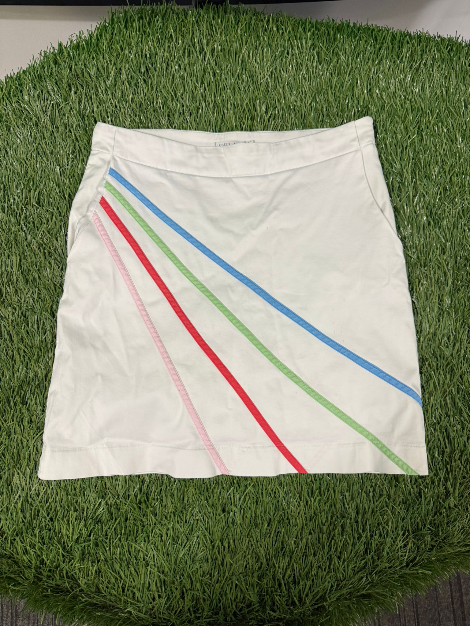 Front view of a white Green Lamb golf skirt with diagonal pastel stripes in pink, red, green, and blue