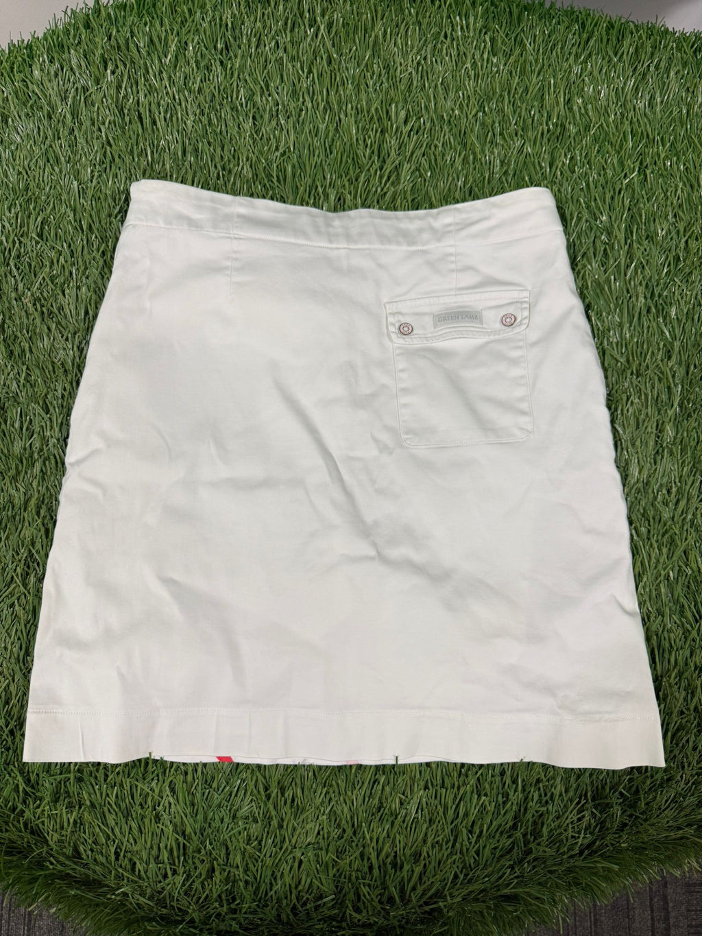 Back view of white Green Lamb golf skirt with a buttoned pocket on the right