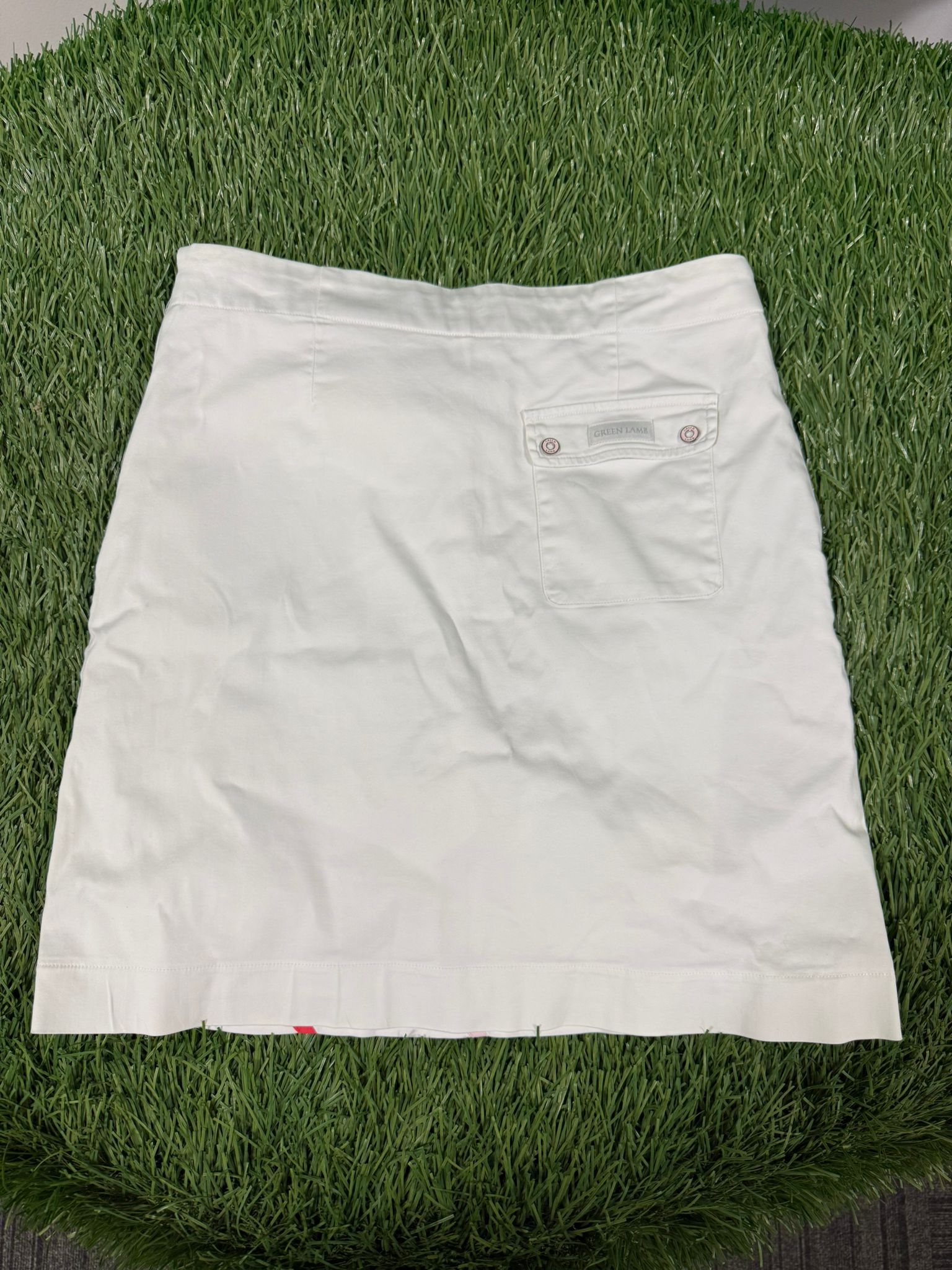Back view of white Green Lamb golf skirt with a buttoned pocket on the right