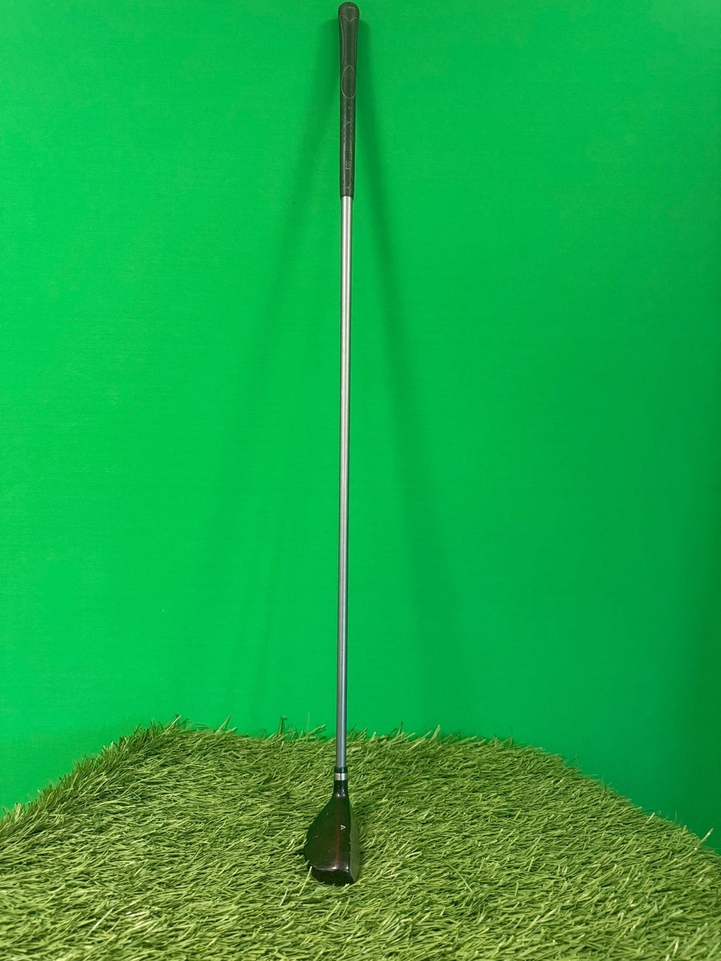 Wilson Deep Red 4 hybrid golf club standing upright on synthetic grass with green background