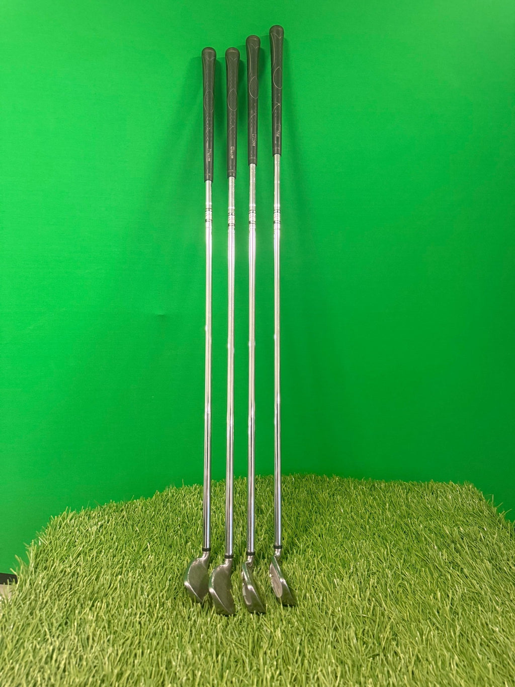 Wilson Deep Red 5, 6, 8, and 9 irons standing upright on artificial grass against a green background