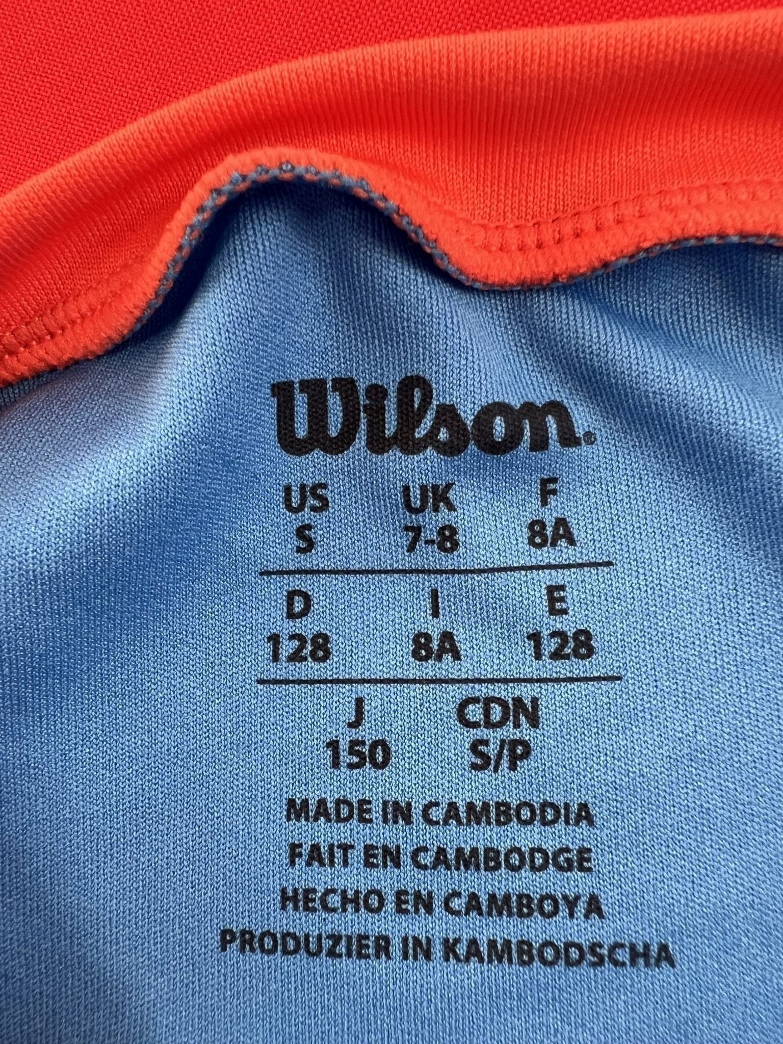 Wilson light blue t-shirt for kids age 7-8 with orange collar accents. Lightweight, breathable fabric for tennis.