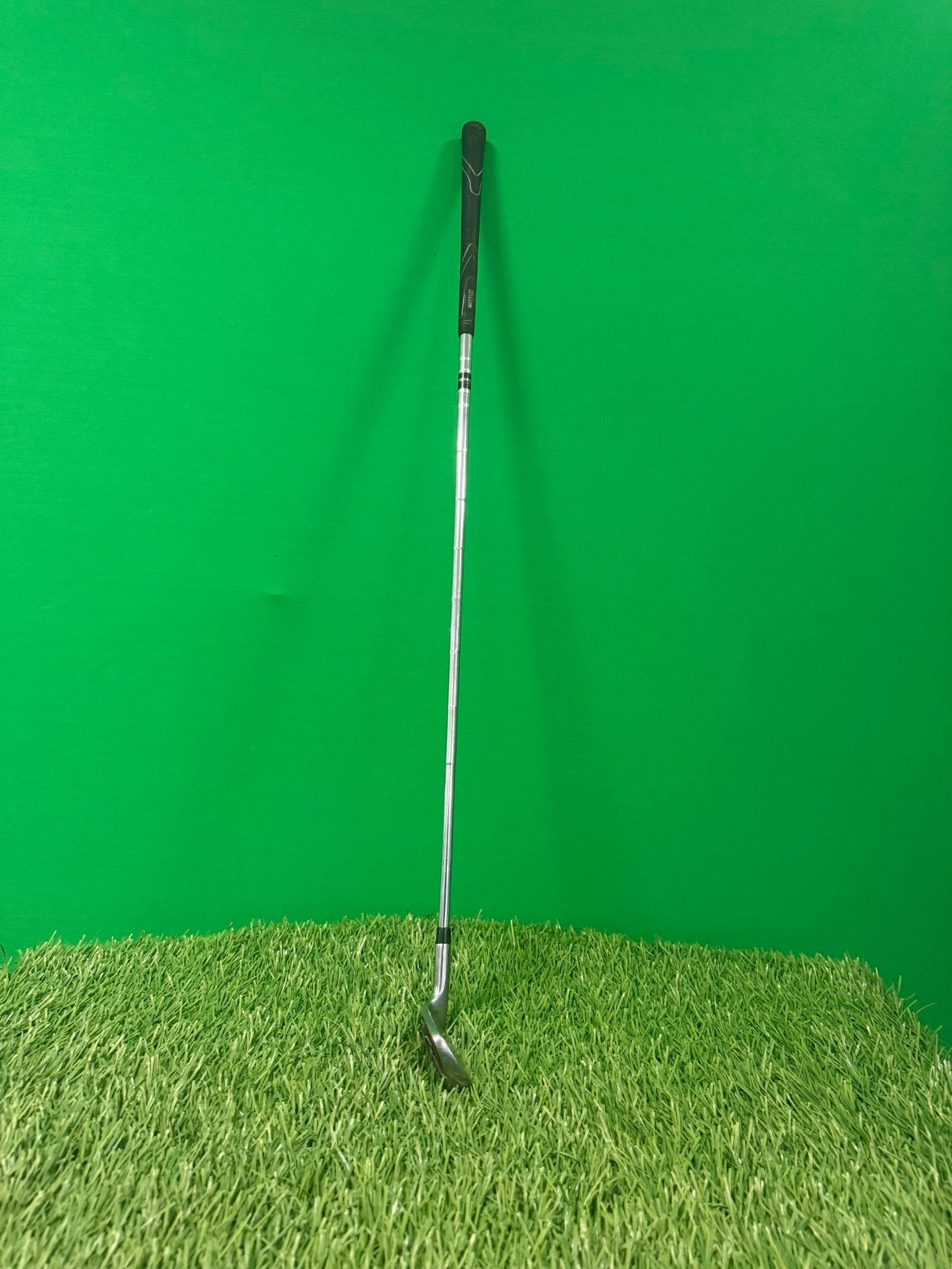 Wilson Prostaff High Launch 9 iron golf club standing upright on artificial grass with a green background