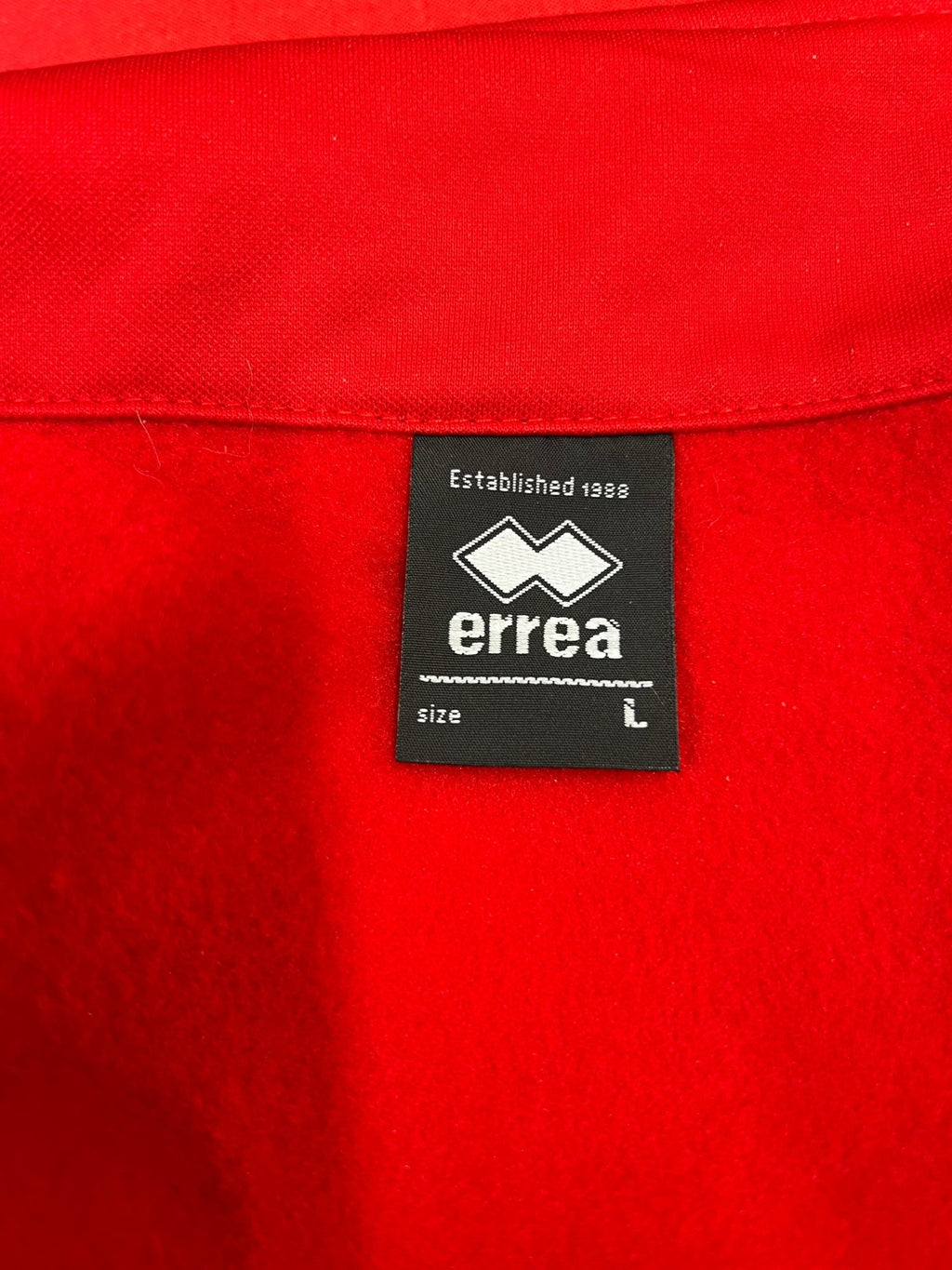 Close-up of Errea brand label inside the Women’s England Volleyball red jacket in size L