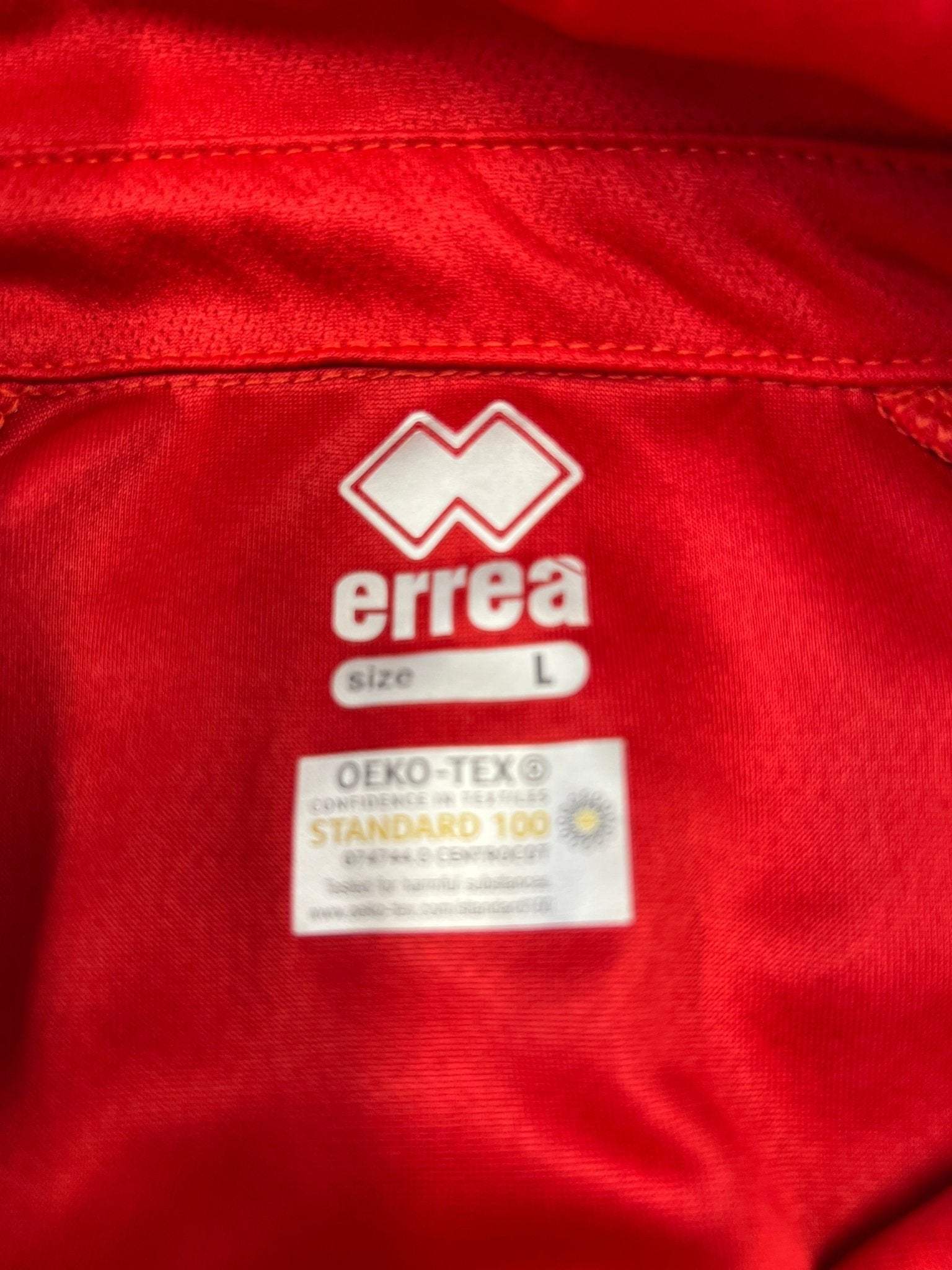 Close-up of Erreà logo and OEKO-TEX label inside the red jersey
