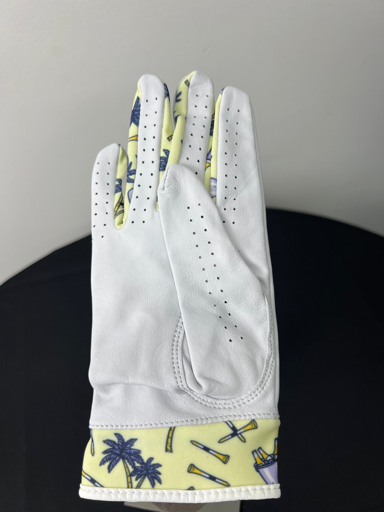 Women's right hand golf glove with tropical palm tree motif at cuff, shown palm down.
