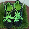 Pair of black running spikes with bright green laces viewed from above