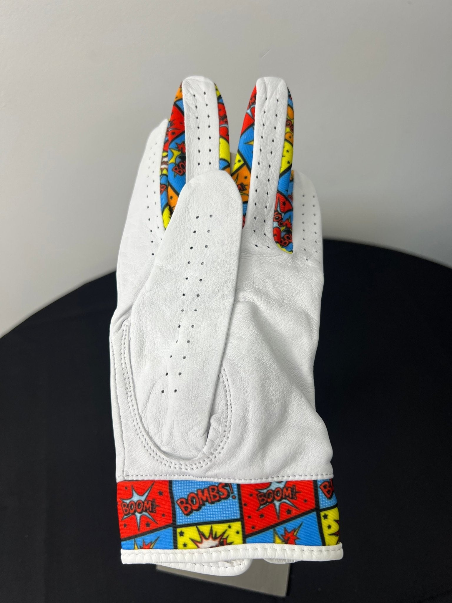 Back view of women's comic motif golf glove showing 'BOOM!' and 'BOMBS!' design