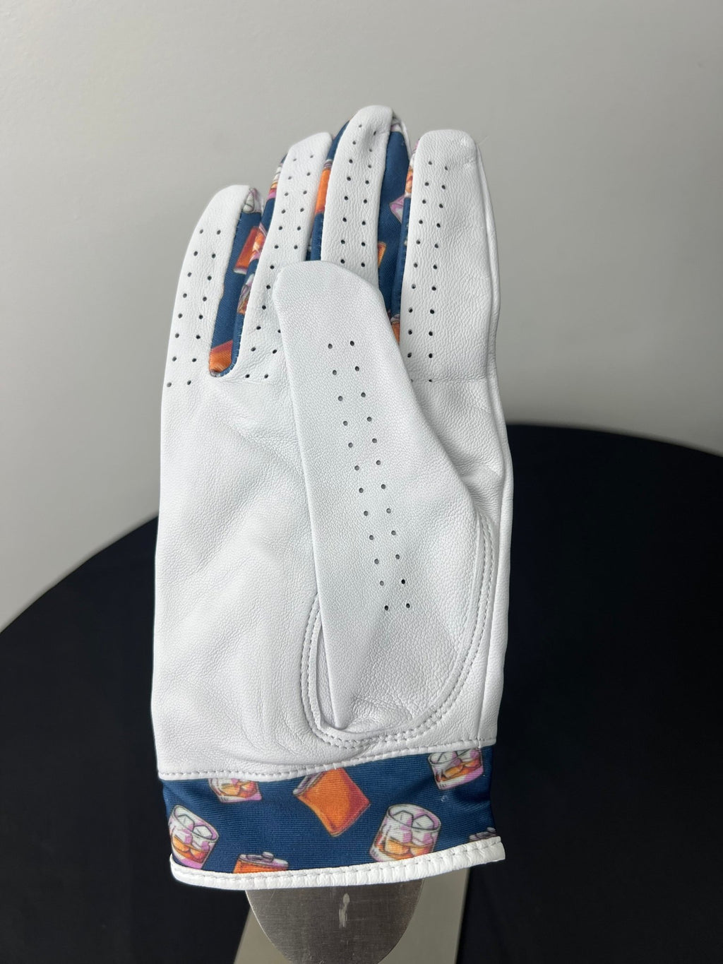 Back view of a women's white Skins Golf glove with whiskey and flask pattern on edge