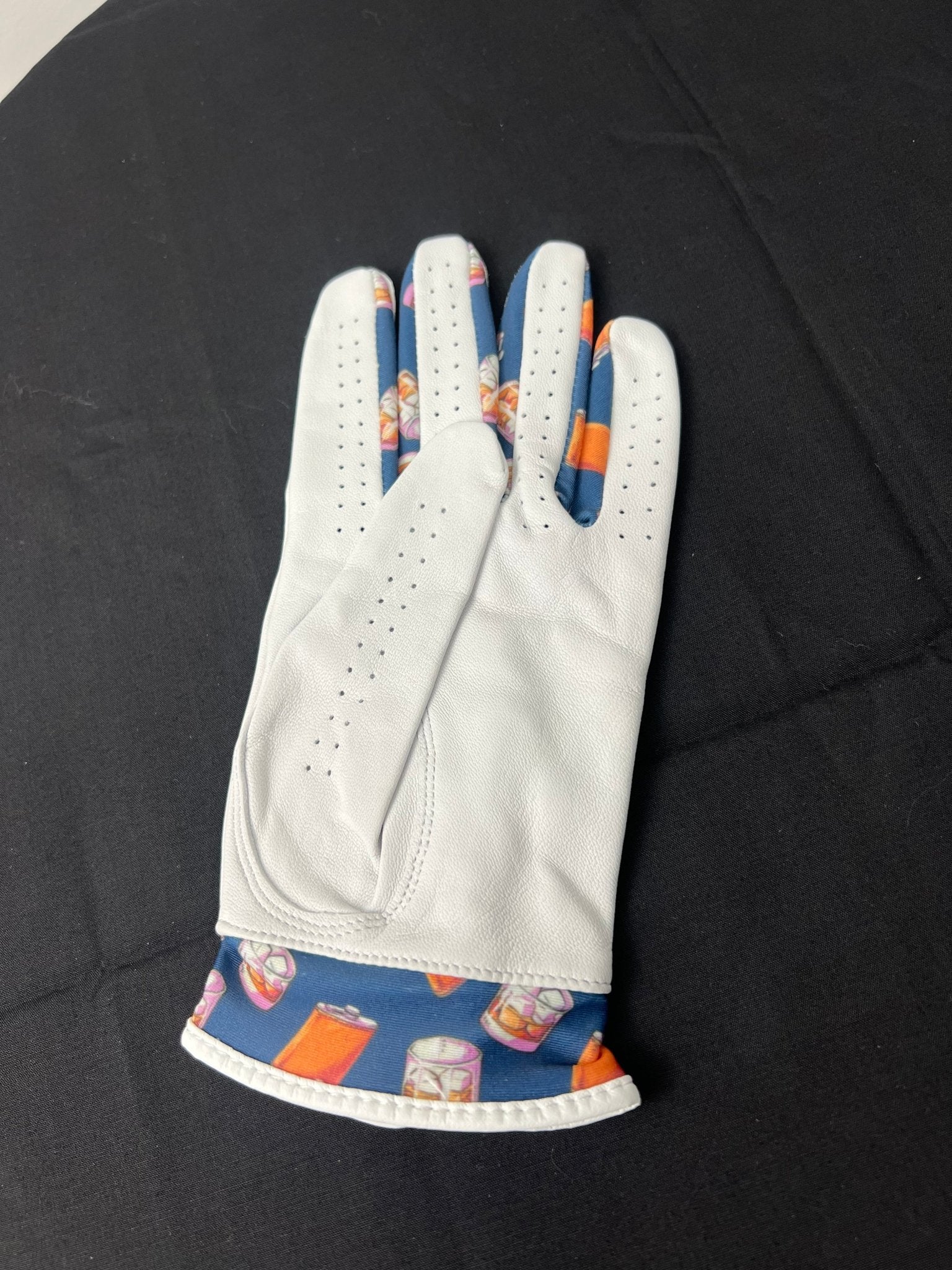 Back view of women's white golf glove with colorful whiskey glasses and flask design at the cuff