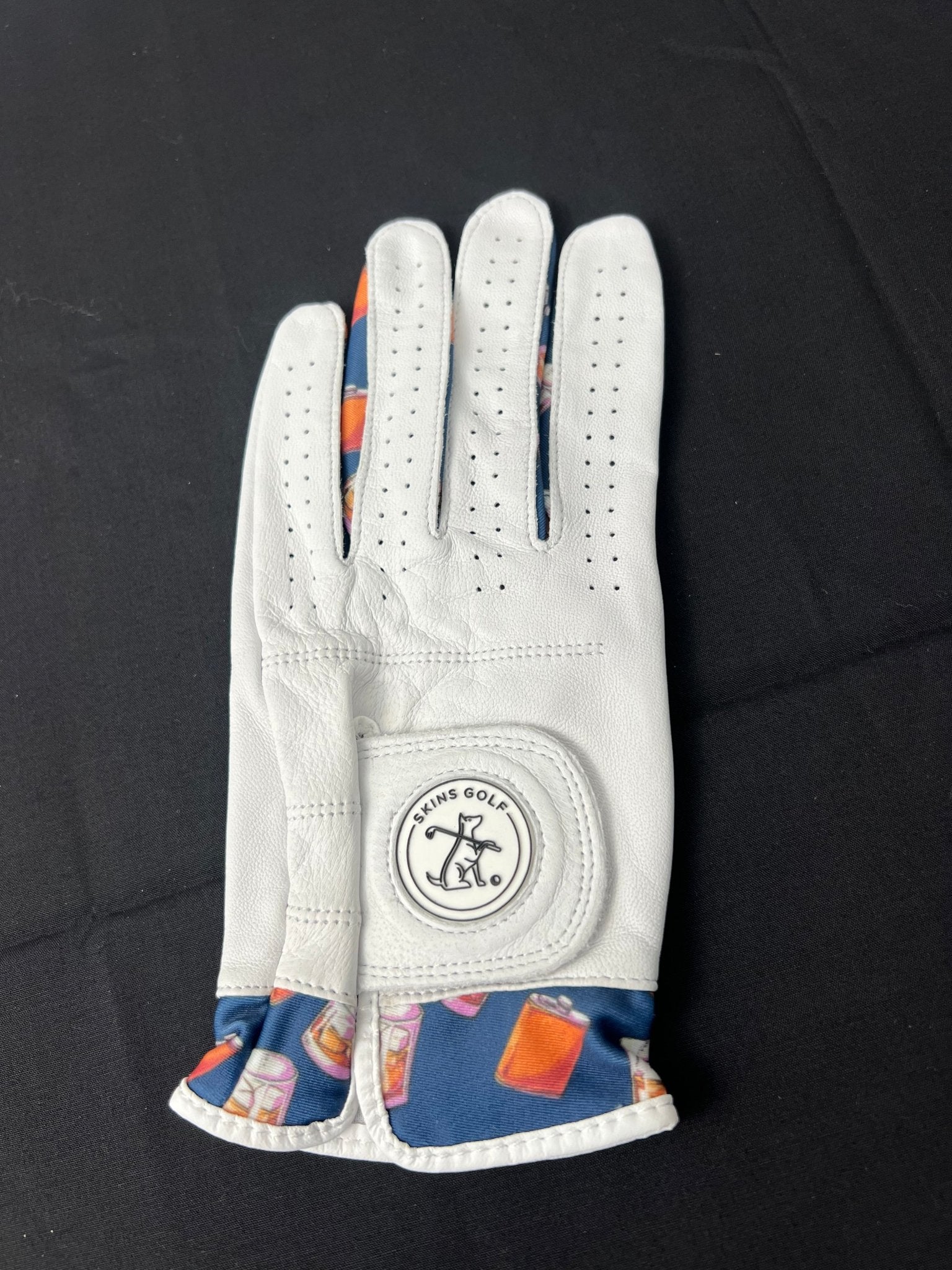 Women's white leather golf glove with whiskey motif by Skins Golf shown on a black background