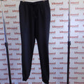 Black Under Armour tracksuit bottoms hanging on rail against kitround backdrop