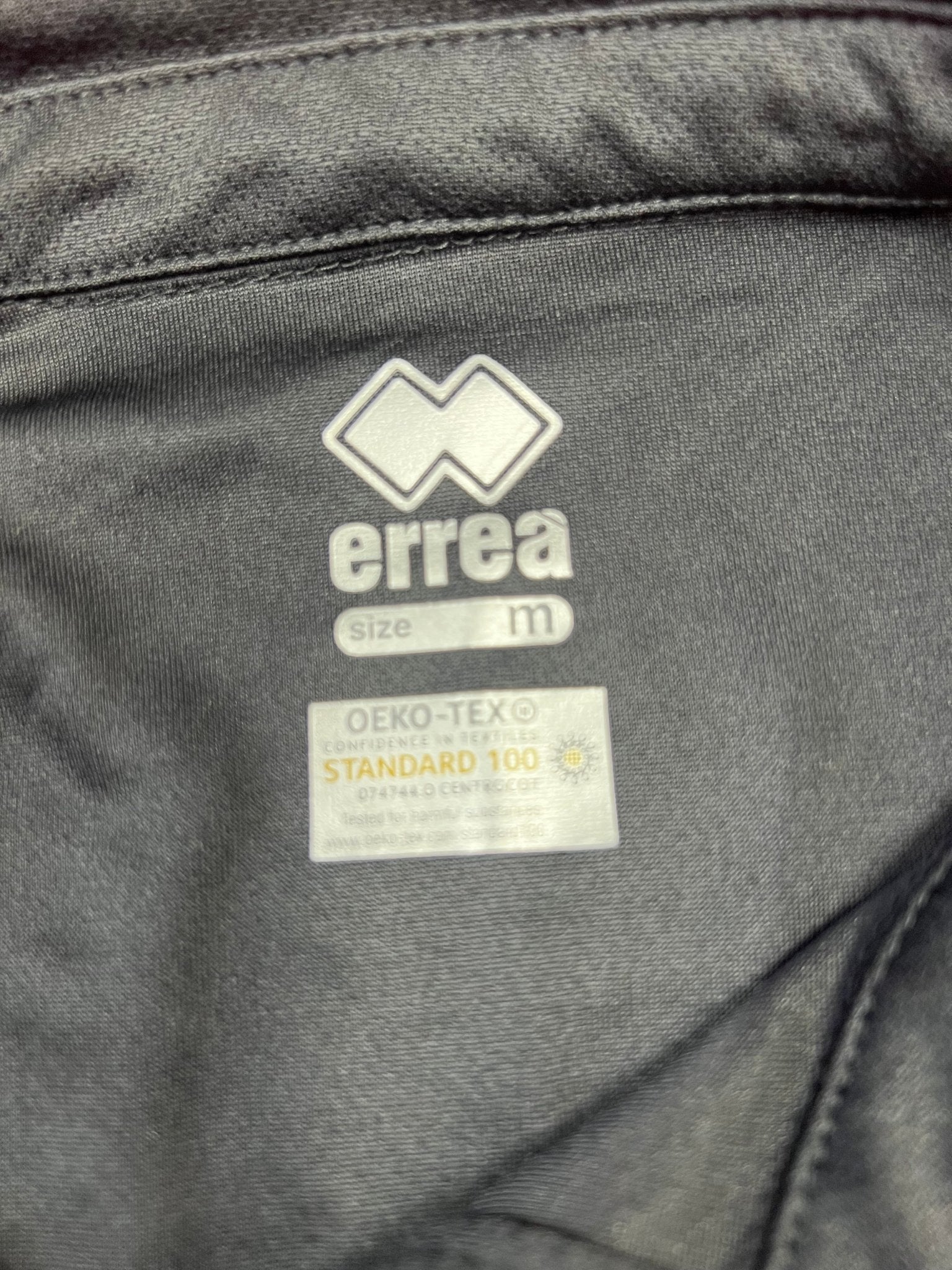 Close-up of Erreà logo and OEKO-TEX Standard 100 tag inside collar