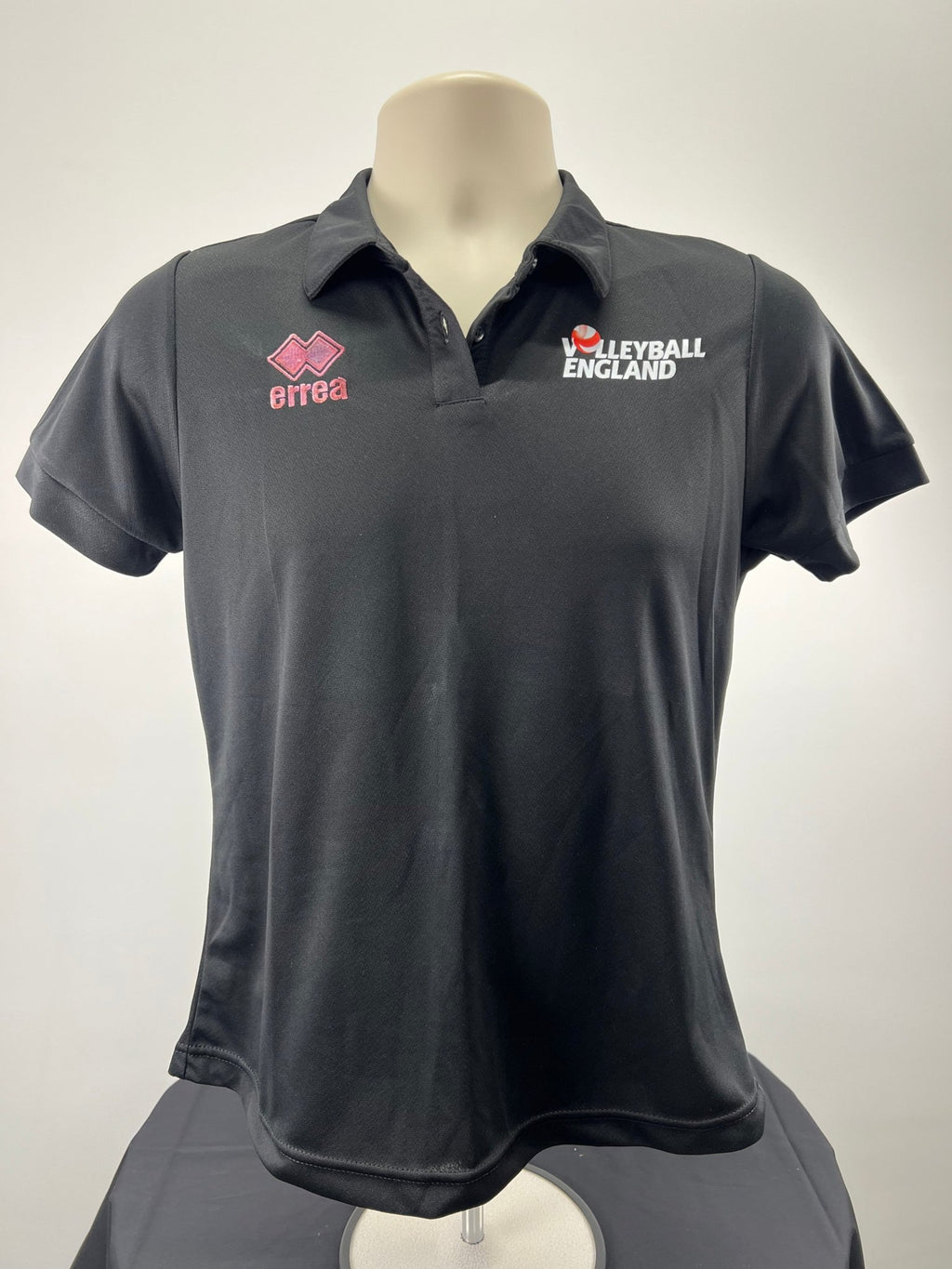 Front view of black Volleyball England women's polo shirt with embroidered logos