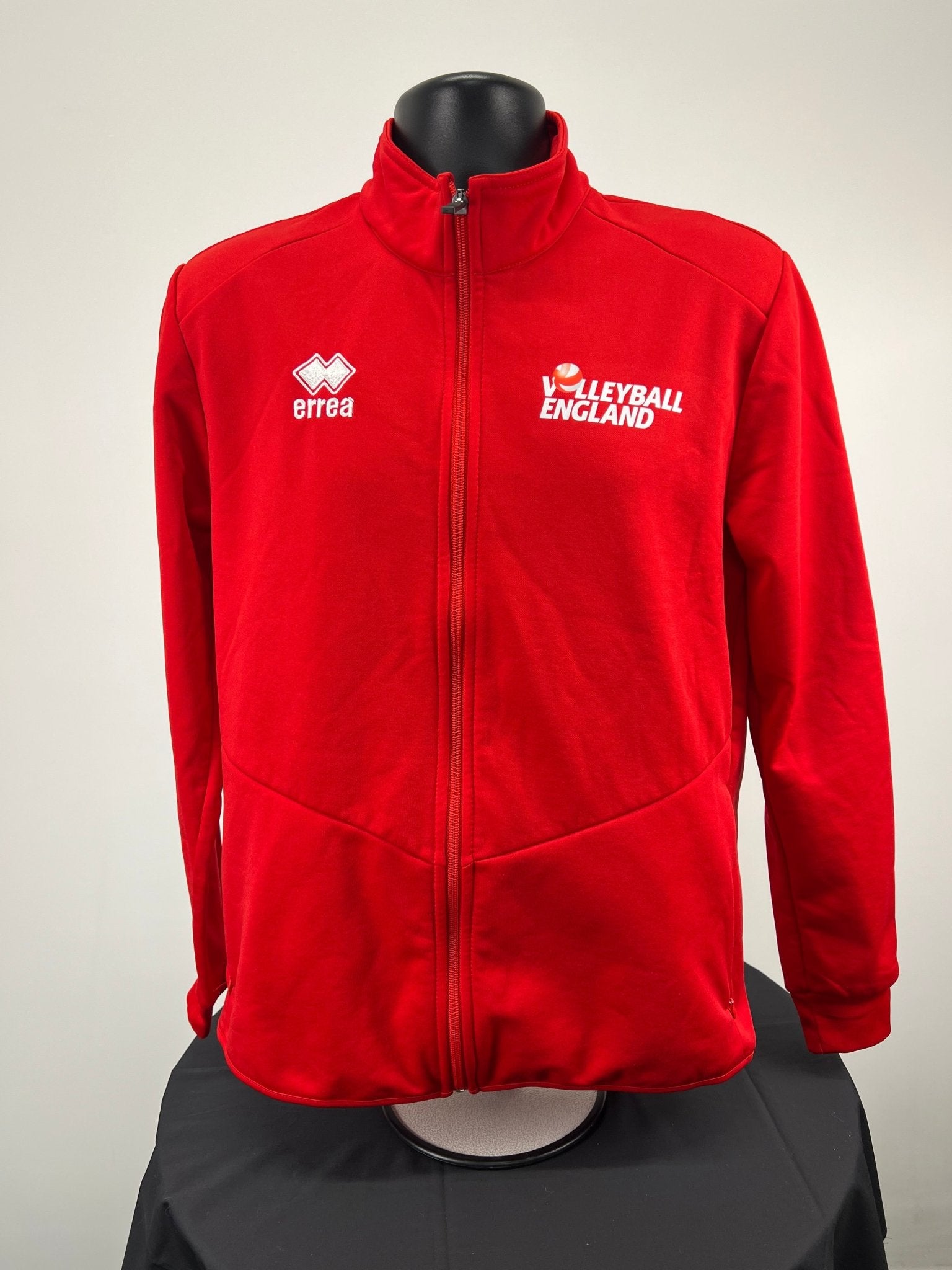 Front view of red Women’s Volleyball England full zip jacket with logos and zip-up pockets on mannequin