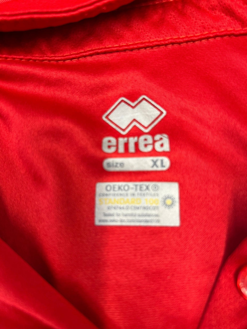 Close-up of Errea label and Oeko-Tex tag inside the red polo shirt XL