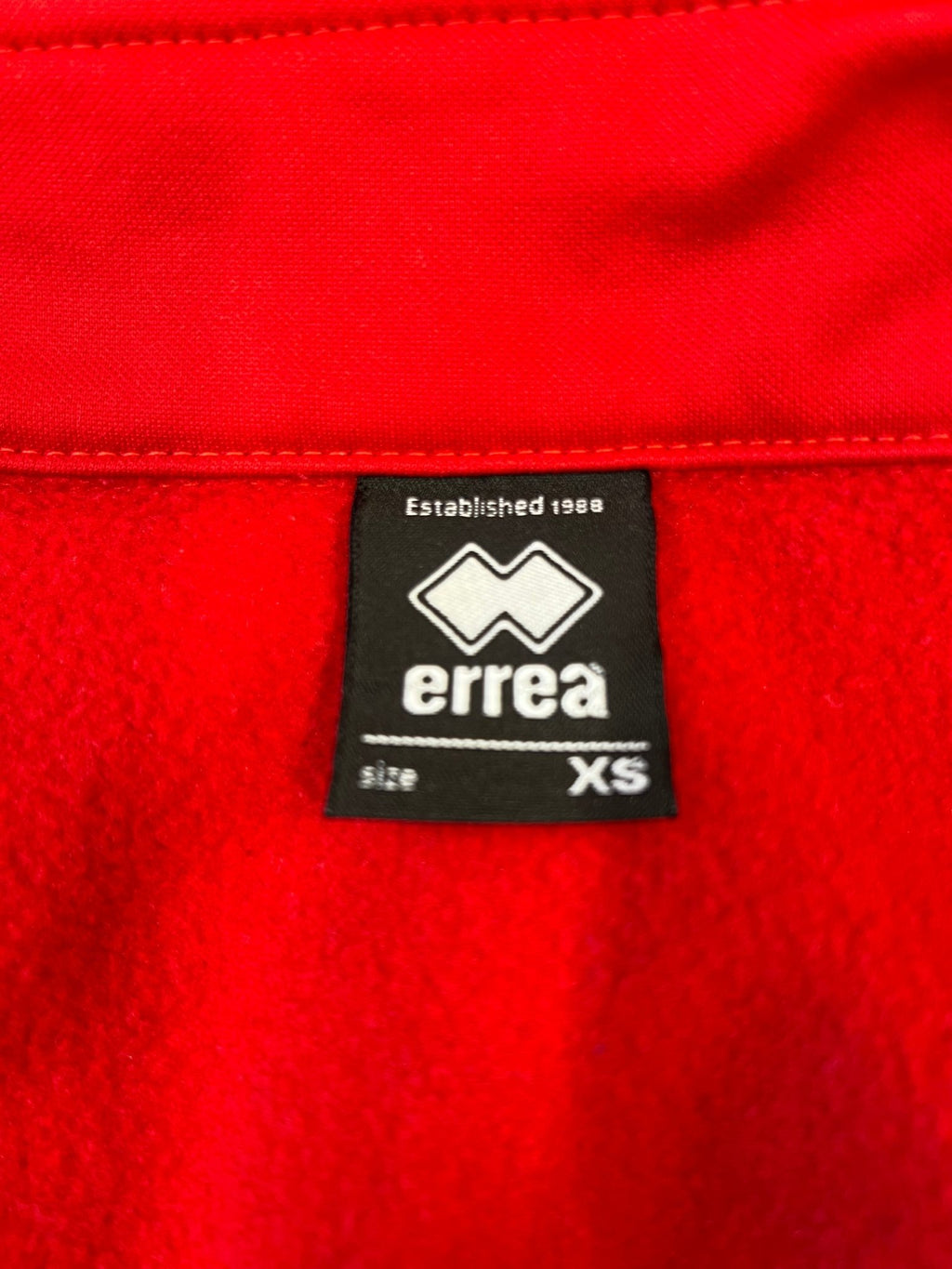 Close-up of Errea brand label inside the collar indicating size XS