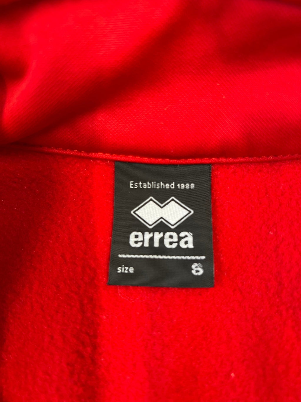 Close-up of Errea brand label showing size S inside the red Volleyball England jacket